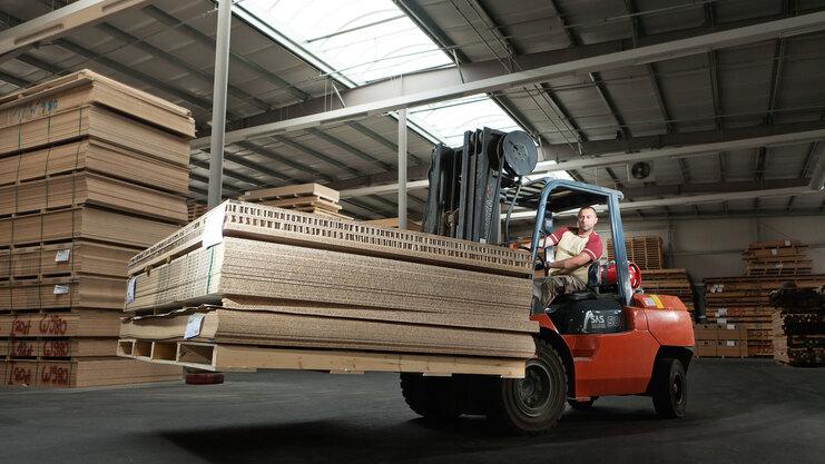Gabelstapler transportiert Holz und Holzpaletten in Lager