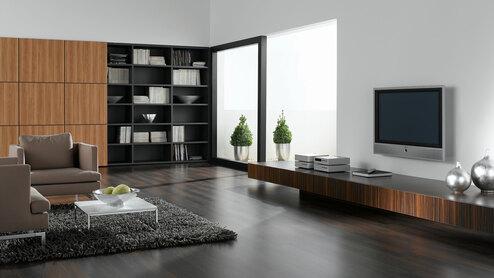 Wohnraumimpression mit verschieden dunklen Holzoberflächen für Einbauschrank, Sideboard und Bodenbelag